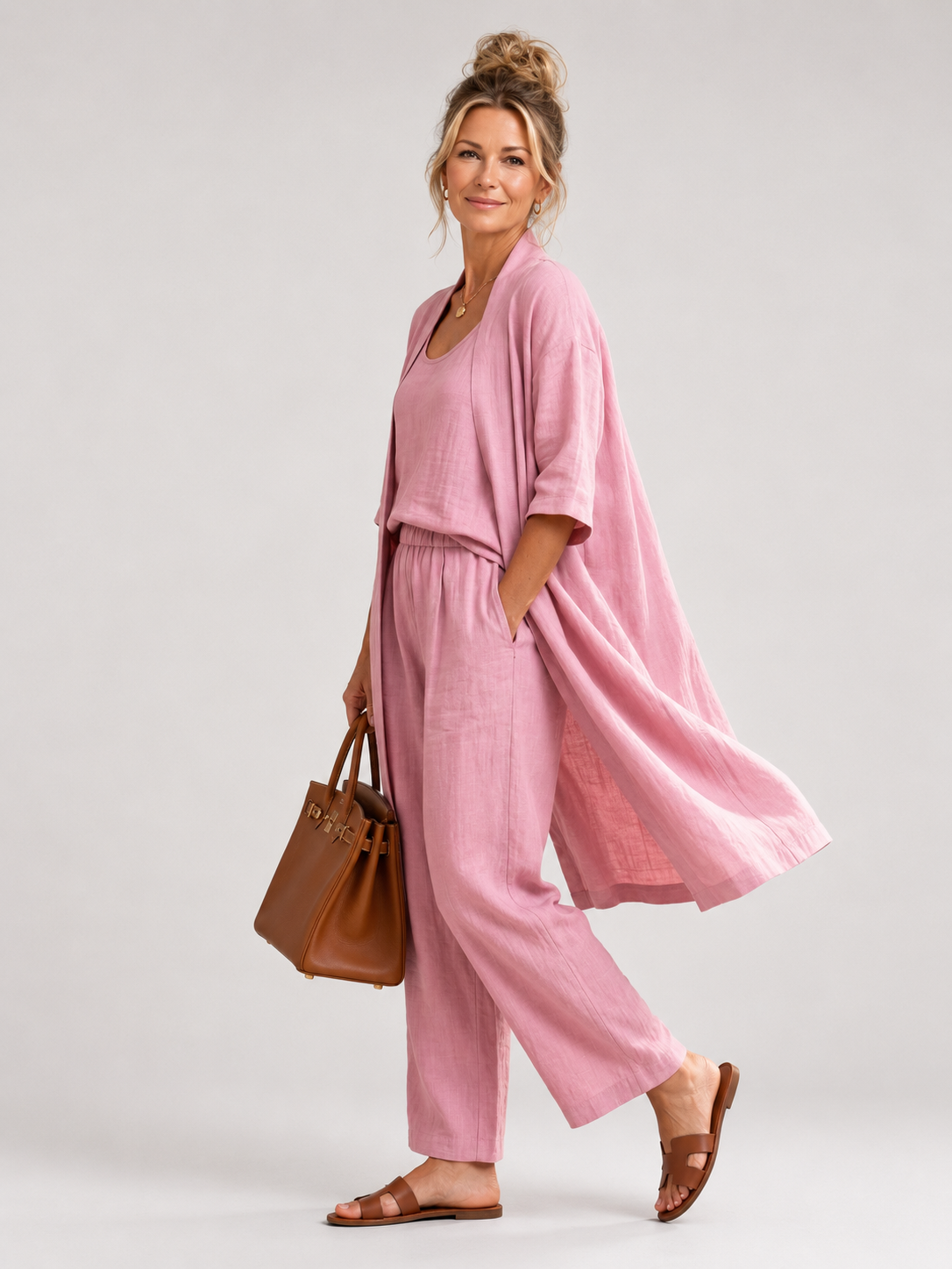 Femme portant un ensemble trois pièces avec haut, pantalon large et pièce ouverte assortie, coloris rose