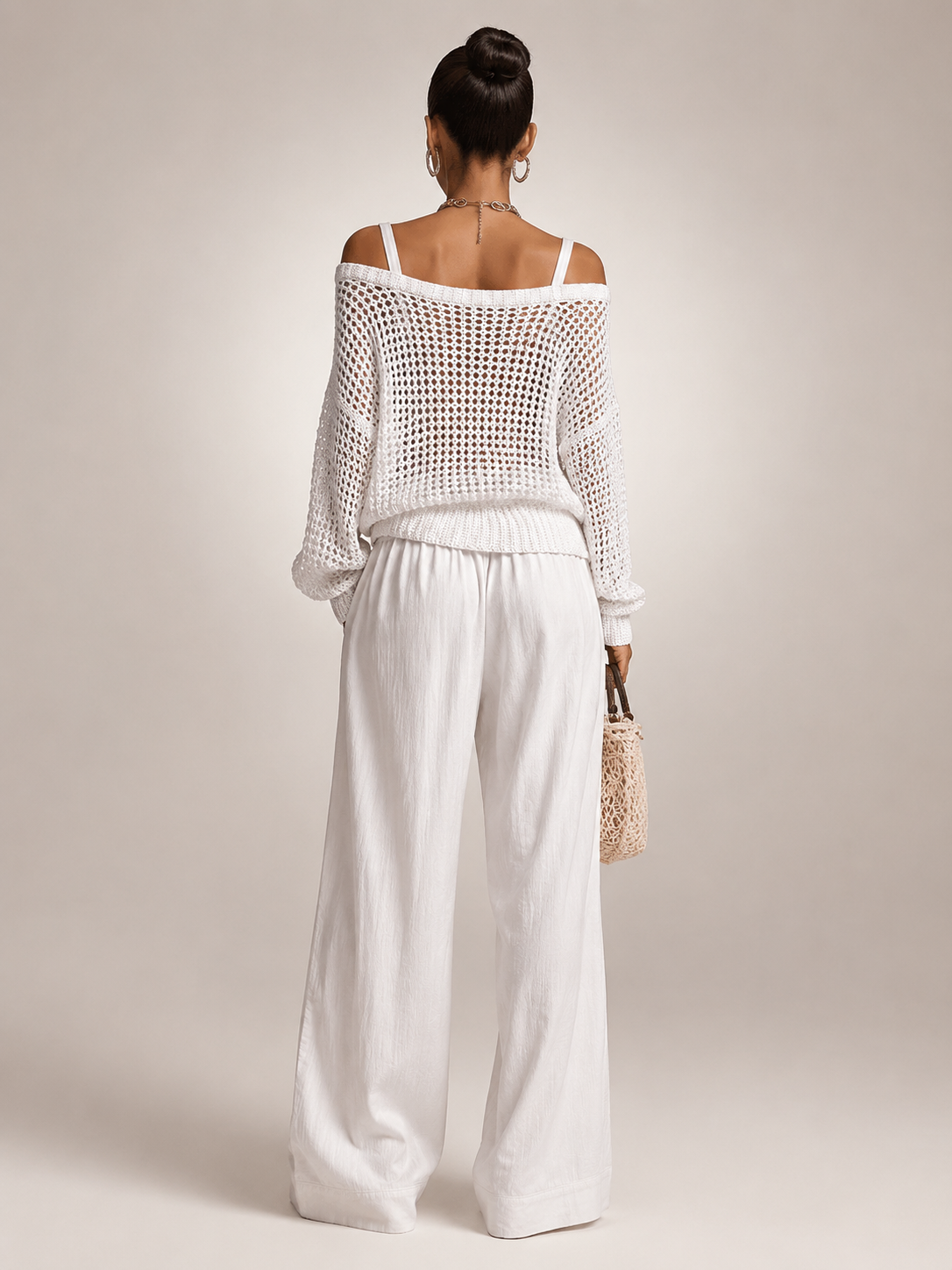 Femme portant un ensemble deux pièces avec haut en maille épaules dénudées et pantalon large, coloris blanc