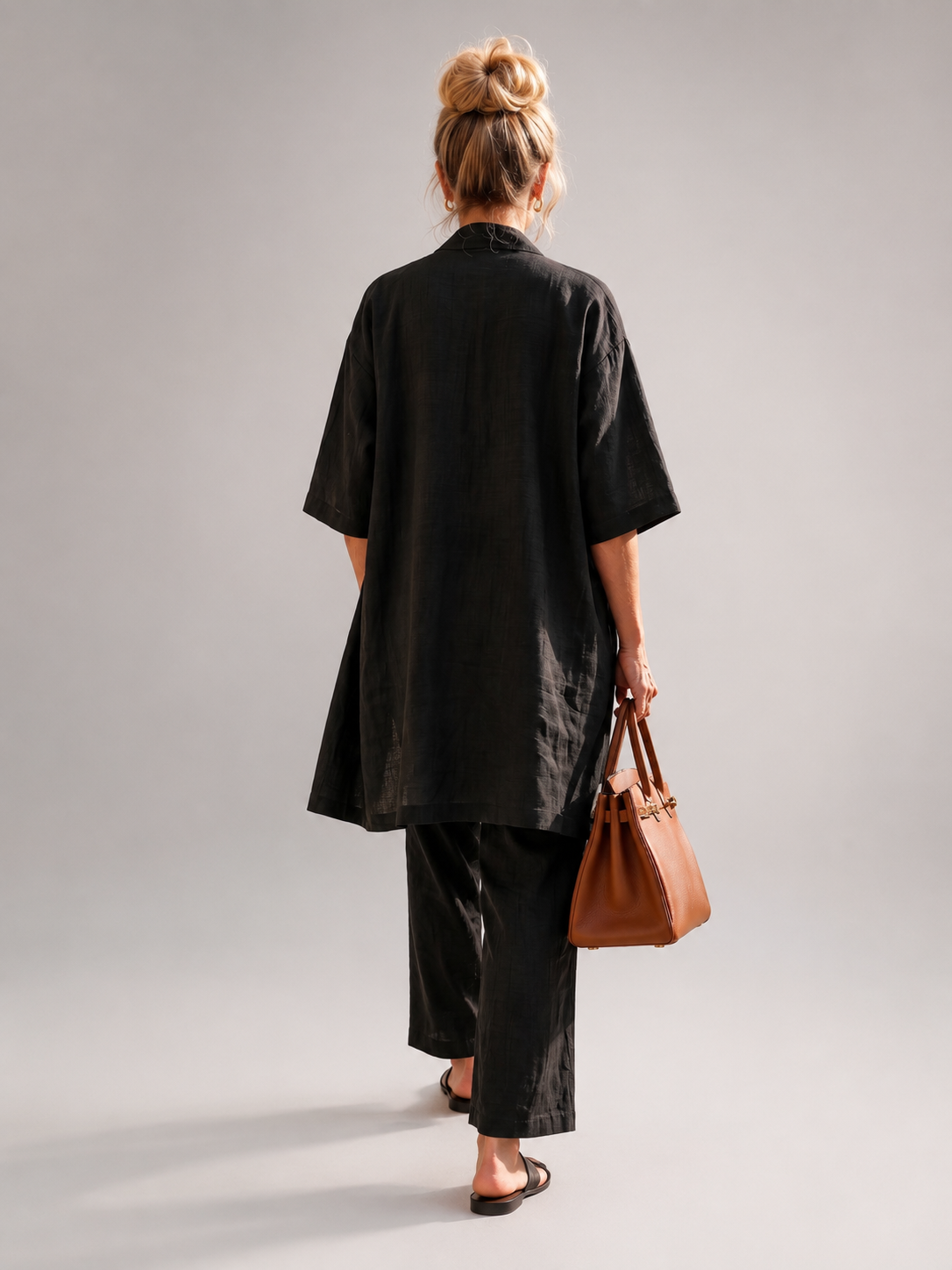 Femme portant un ensemble trois pièces avec haut, pantalon large et pièce ouverte assortie, coloris noir