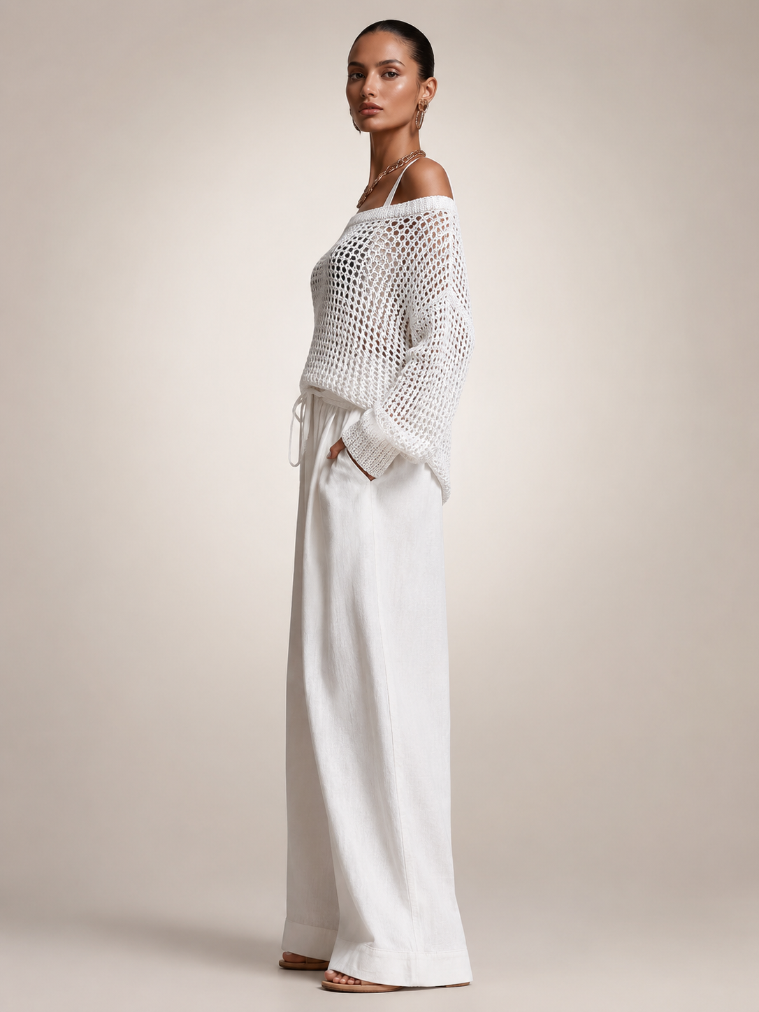 Femme portant un ensemble deux pièces avec haut en maille épaules dénudées et pantalon large, coloris blanc