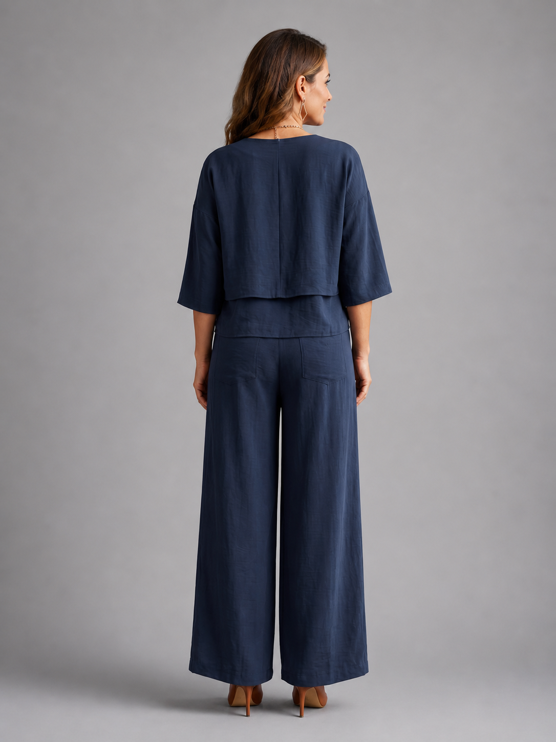 Femme portant un ensemble deux pièces avec haut superposé et pantalon à jambes larges, coloris bleu marine