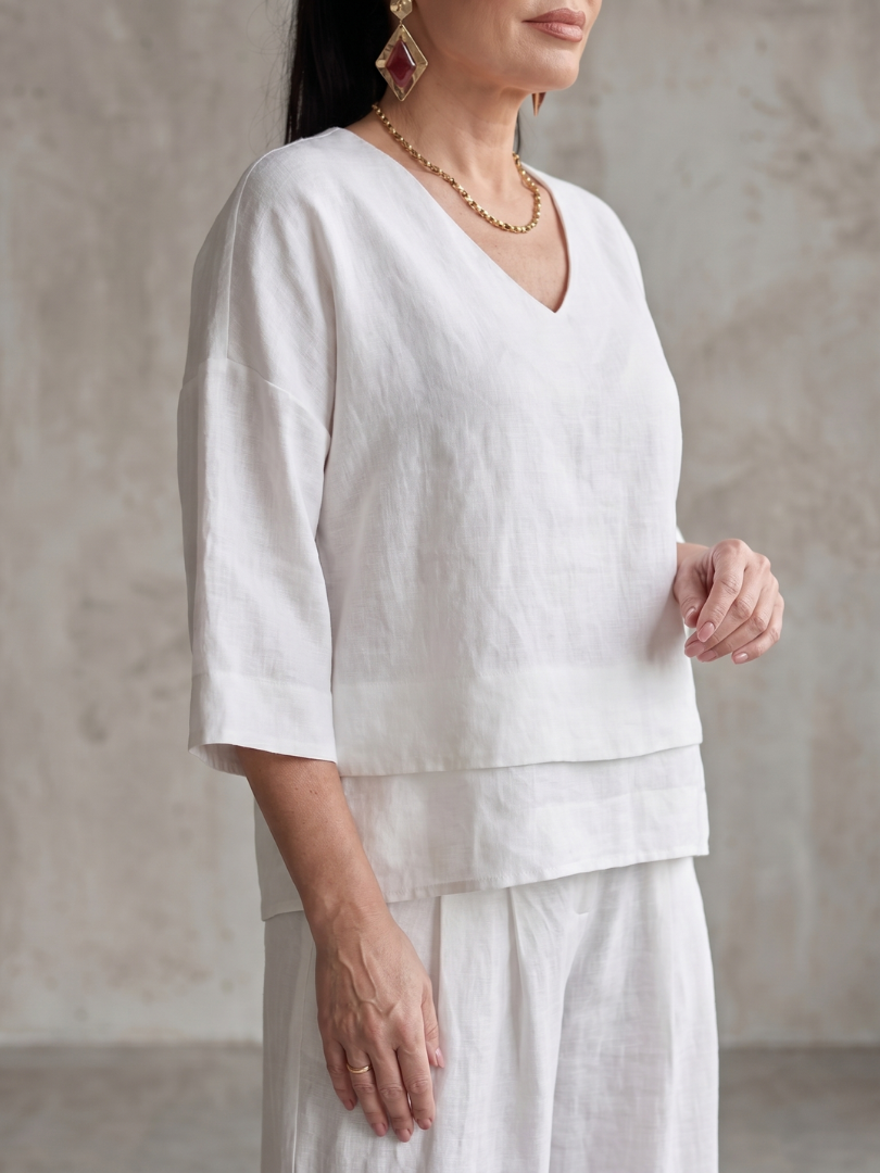 Femme portant un ensemble deux pièces avec haut superposé et pantalon à jambes larges, coloris blanc