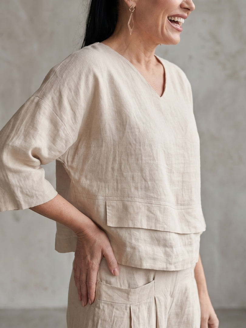 Femme portant un ensemble deux pièces avec haut superposé et pantalon à jambes larges, coloris beige