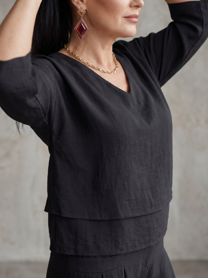 Femme portant un ensemble deux pièces avec haut superposé et pantalon à jambes larges, coloris noir