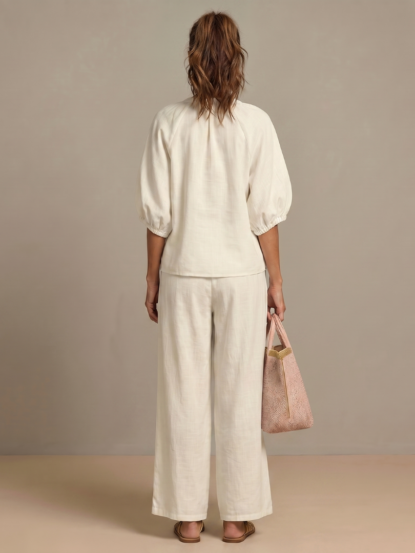 Femme portant un ensemble deux pièces avec blouse zippée et pantalon à jambes larges, coloris blanc