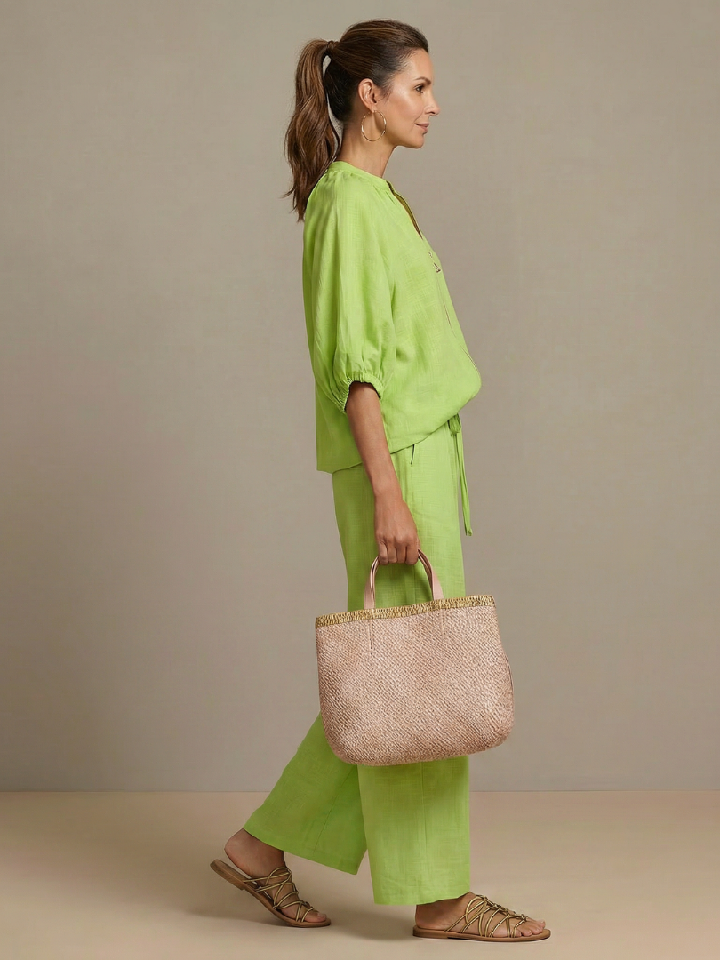 Femme portant un ensemble deux pièces avec blouse zippée et pantalon à jambes larges, coloris vert