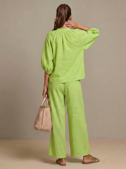 Femme portant un ensemble deux pièces avec blouse zippée et pantalon à jambes larges, coloris vert