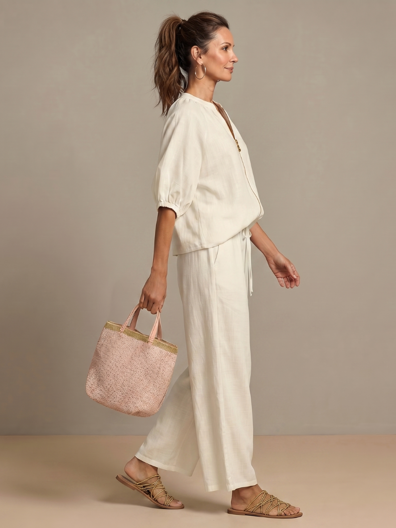 Femme portant un ensemble deux pièces avec blouse zippée et pantalon à jambes larges, coloris blanc