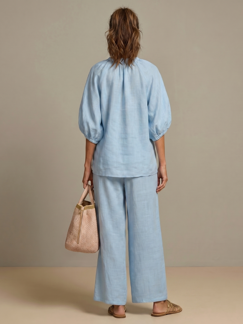 Femme portant un ensemble deux pièces avec blouse zippée et pantalon à jambes larges, coloris bleu