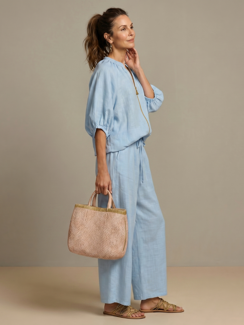 Femme portant un ensemble deux pièces avec blouse zippée et pantalon à jambes larges, coloris bleu