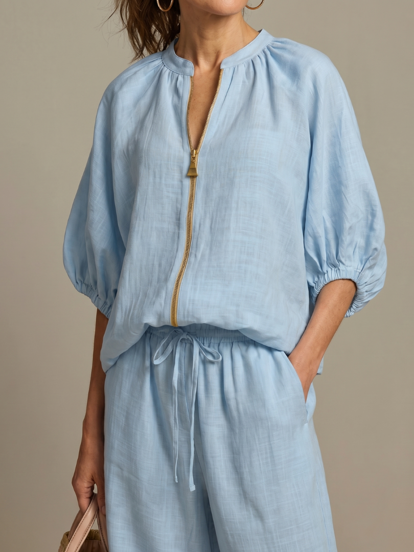 Femme portant un ensemble deux pièces avec blouse zippée et pantalon à jambes larges, coloris bleu