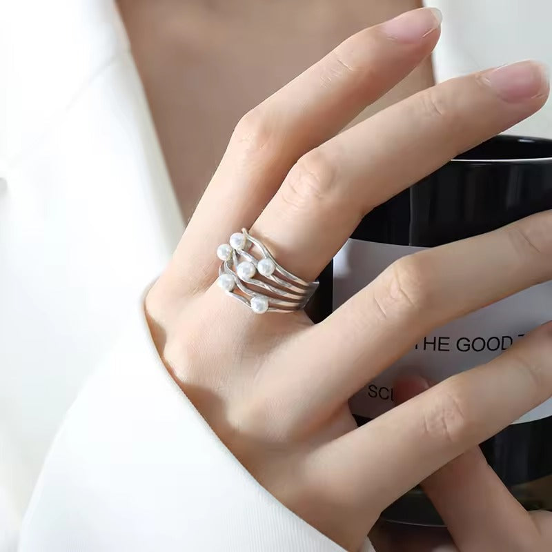 Main portant une bague empilée argentée avec petites perles claires