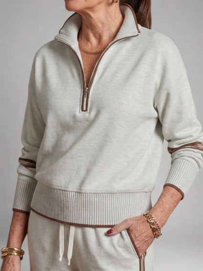 Femme portant un ensemble deux pièces en maille avec haut à col zippé et pantalon large, coloris blanc