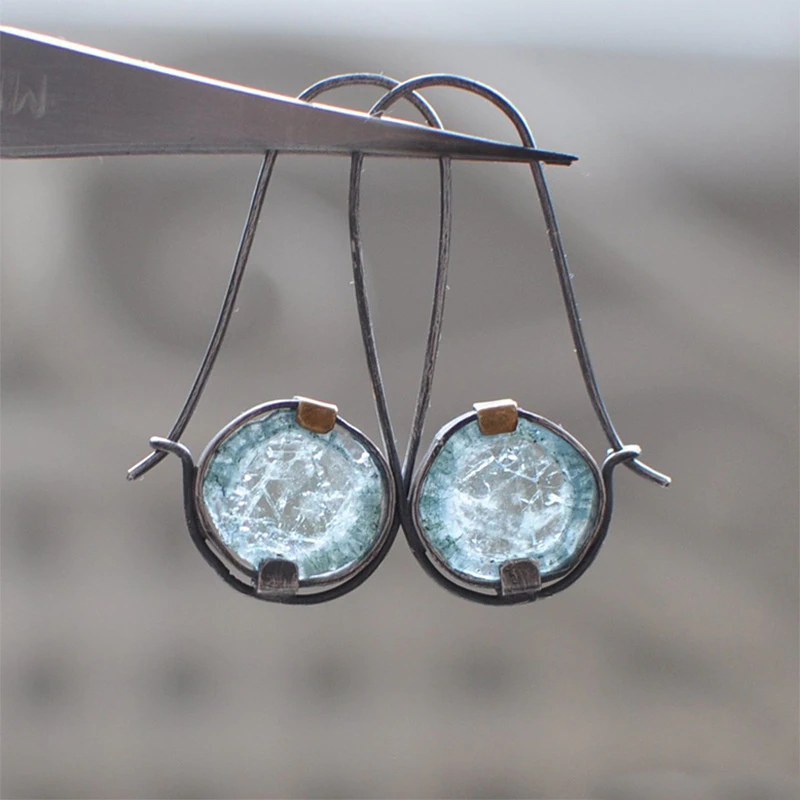 Disque Givré | Boucles d'oreilles avec pierre bleu clair dans un serti sombre – Vue 01