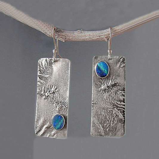 Surface Argentée | Boucles d'oreilles allongées argentées avec petite pierre bleue – Vue 01