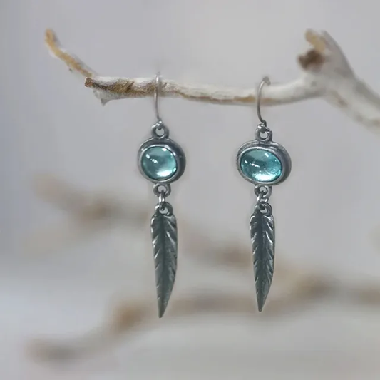 Bleu Plume | Boucles d'oreilles argentées avec plume et pierre bleu clair – Vue 01
