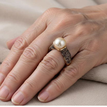 Main portant une bague dorée avec pierre claire ronde